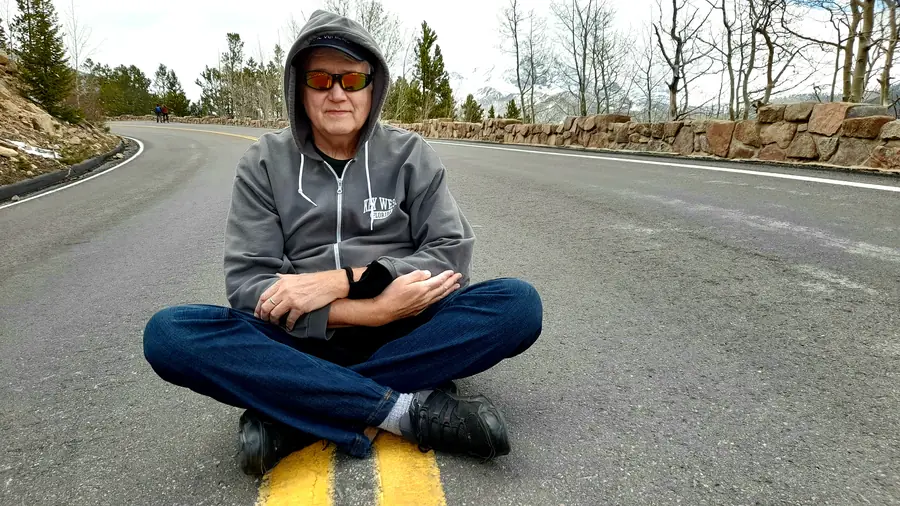 Rick Denzien sitting on a road during an EV road trip